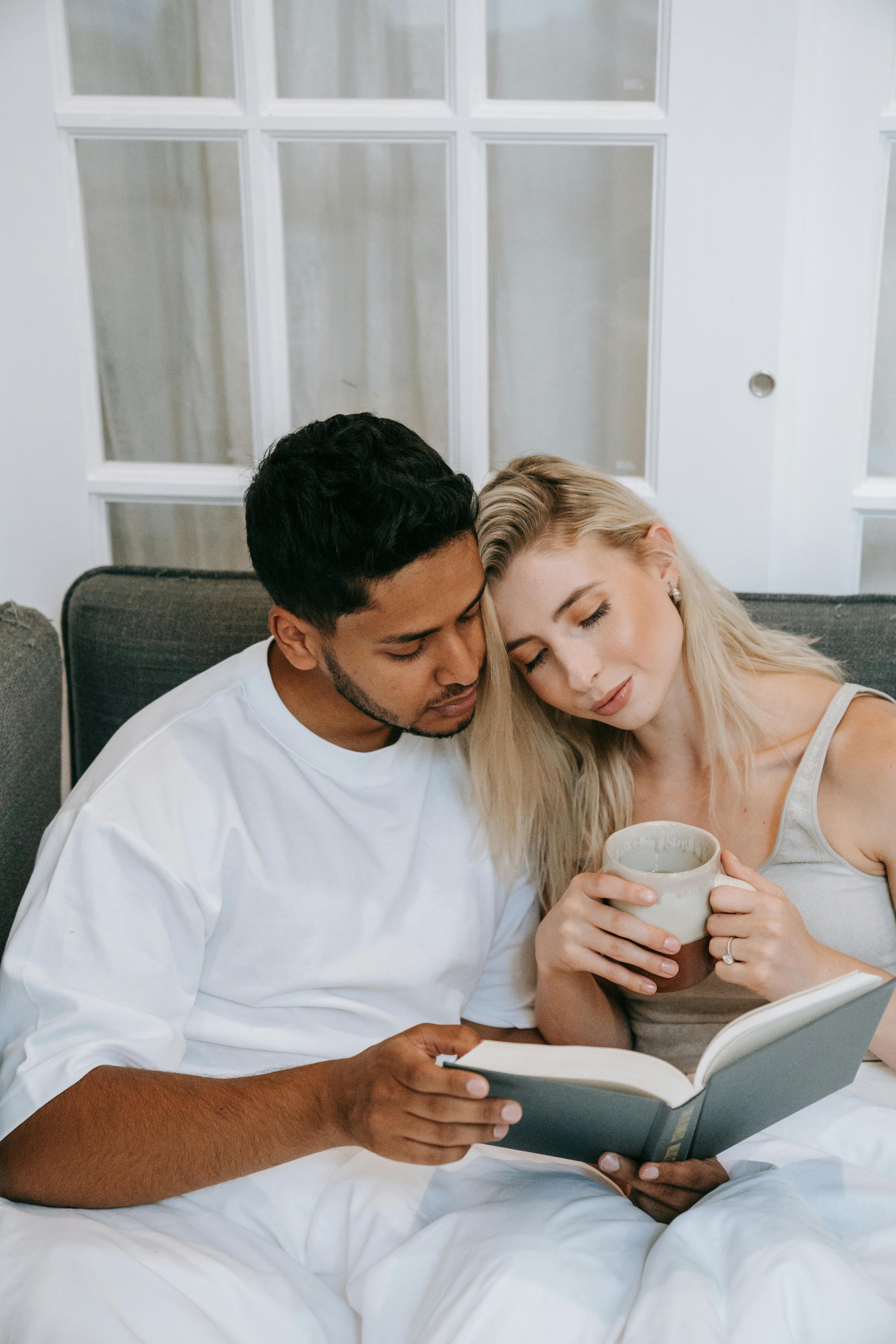 A couple enjoys a quiet morning reading session in a cozy bedroom setting.