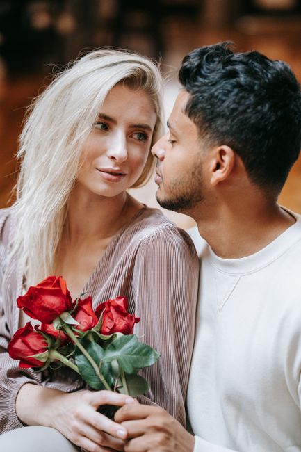 Fotomural Pareja amorosa en interiores, sosteniendo rosas y compartiendo un momento romántico.