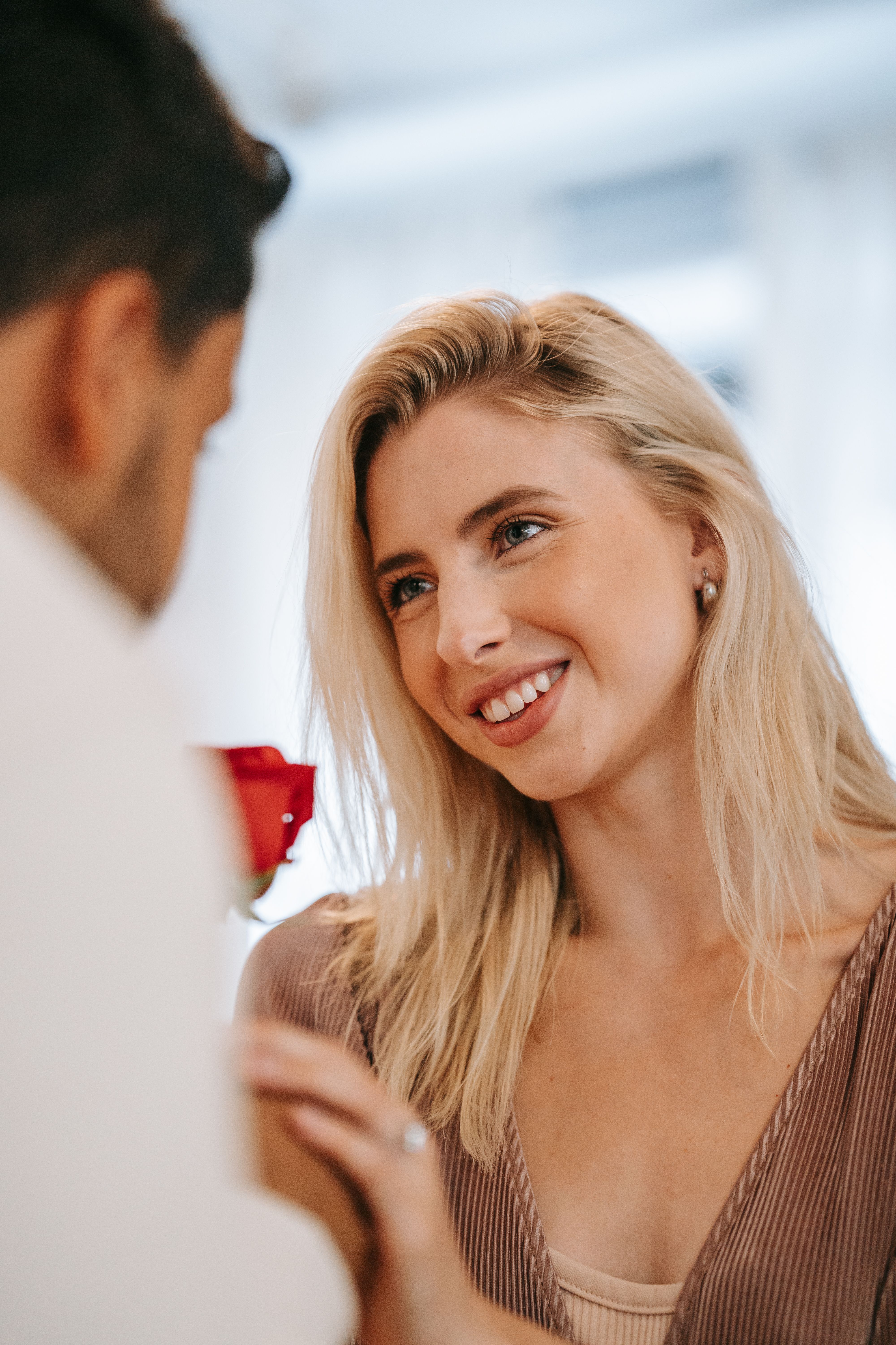 Lovely moment of a couple sharing smiles and love with a rose indoors.