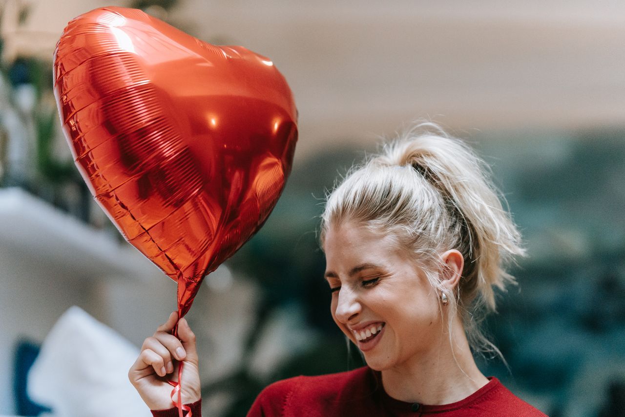 a joyful woman holding a heart shaped balloon adding happiness and war