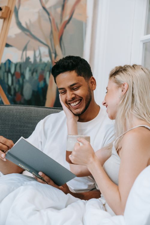 Free Happy couple enjoying a relaxed morning in bed, reading together. Stock Photo