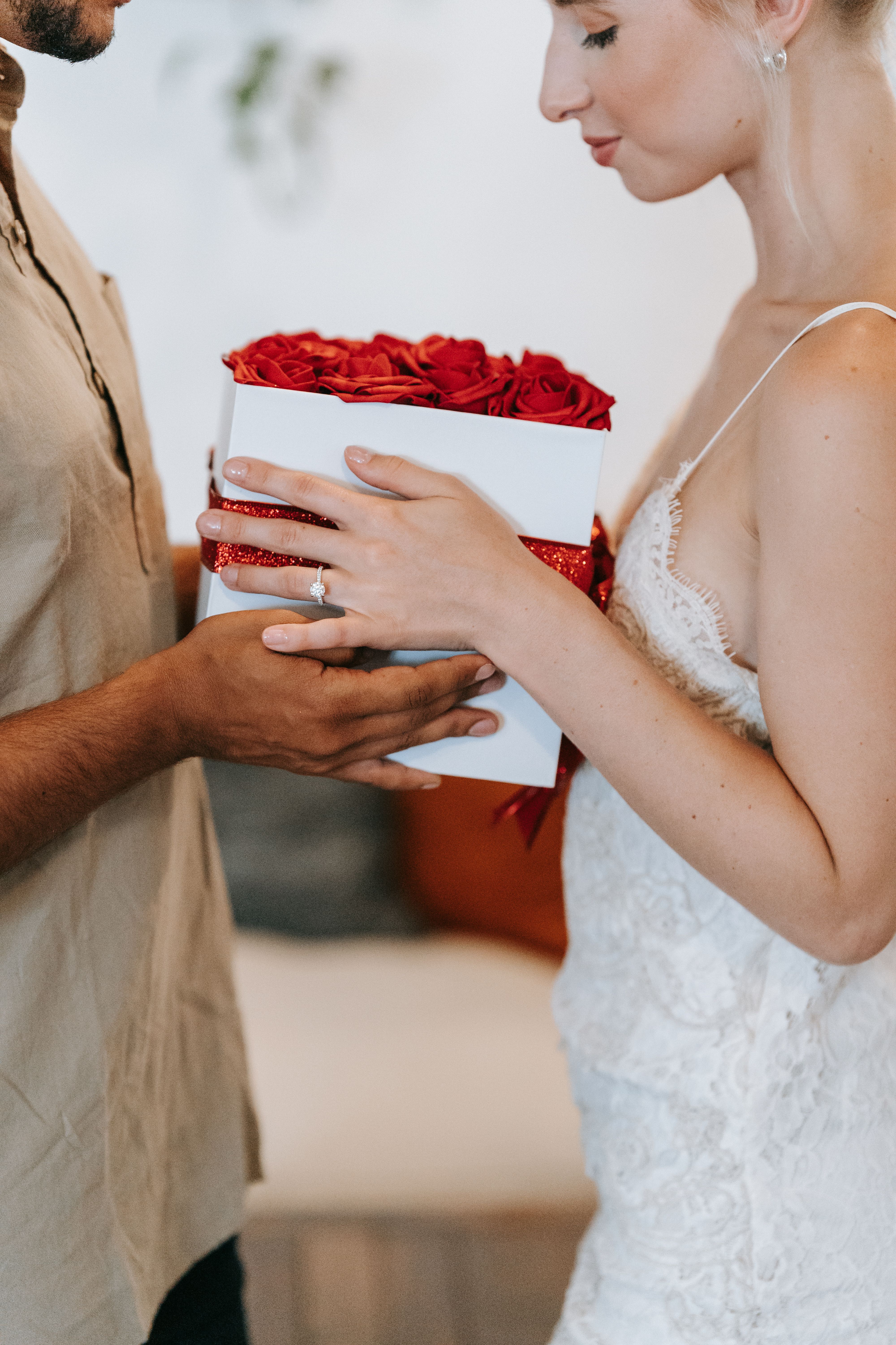 A couple shares a romantic moment exchanging a rose-filled gift box, symbolizing love and affection.