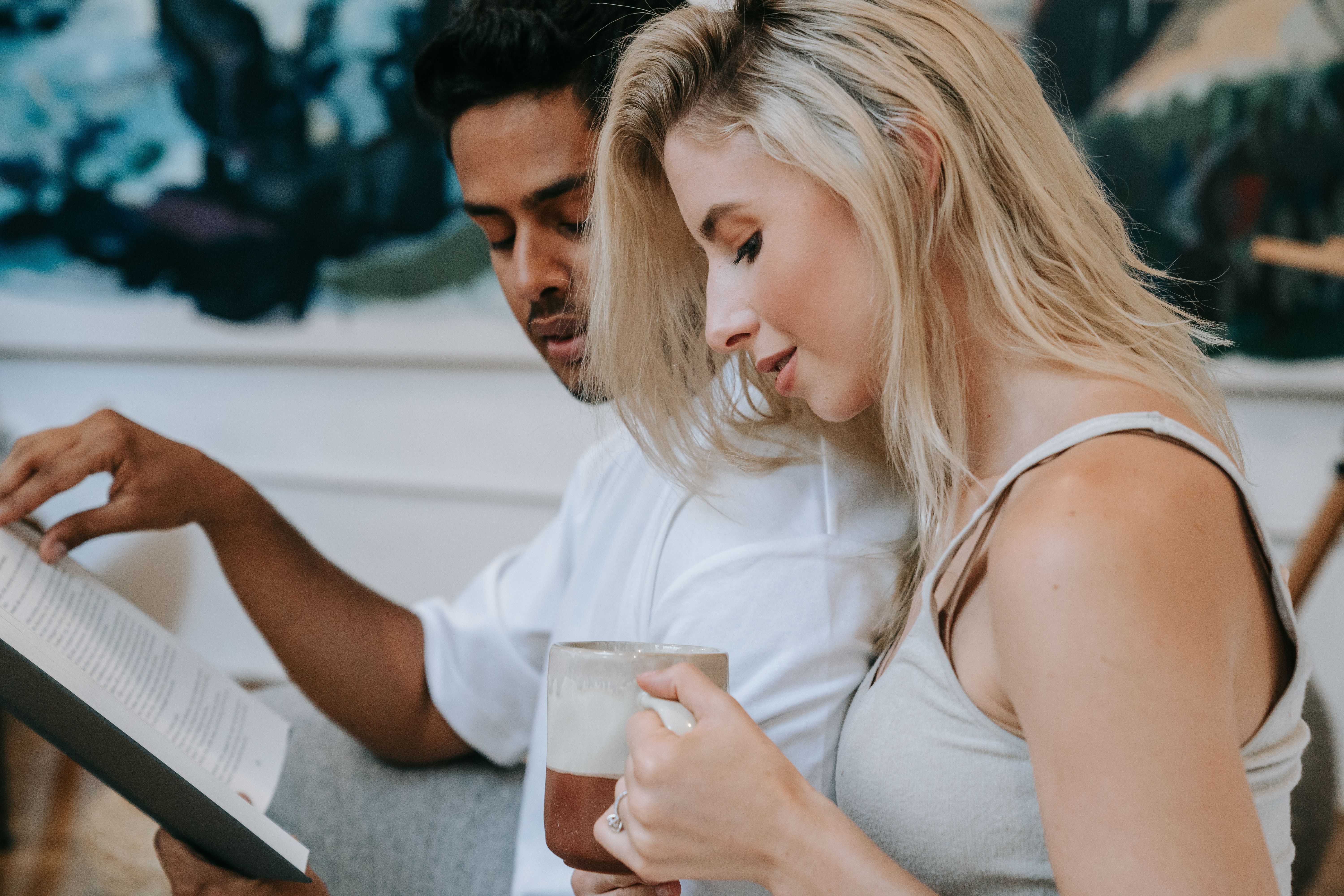 A couple enjoying a quiet moment reading and sipping coffee indoors.