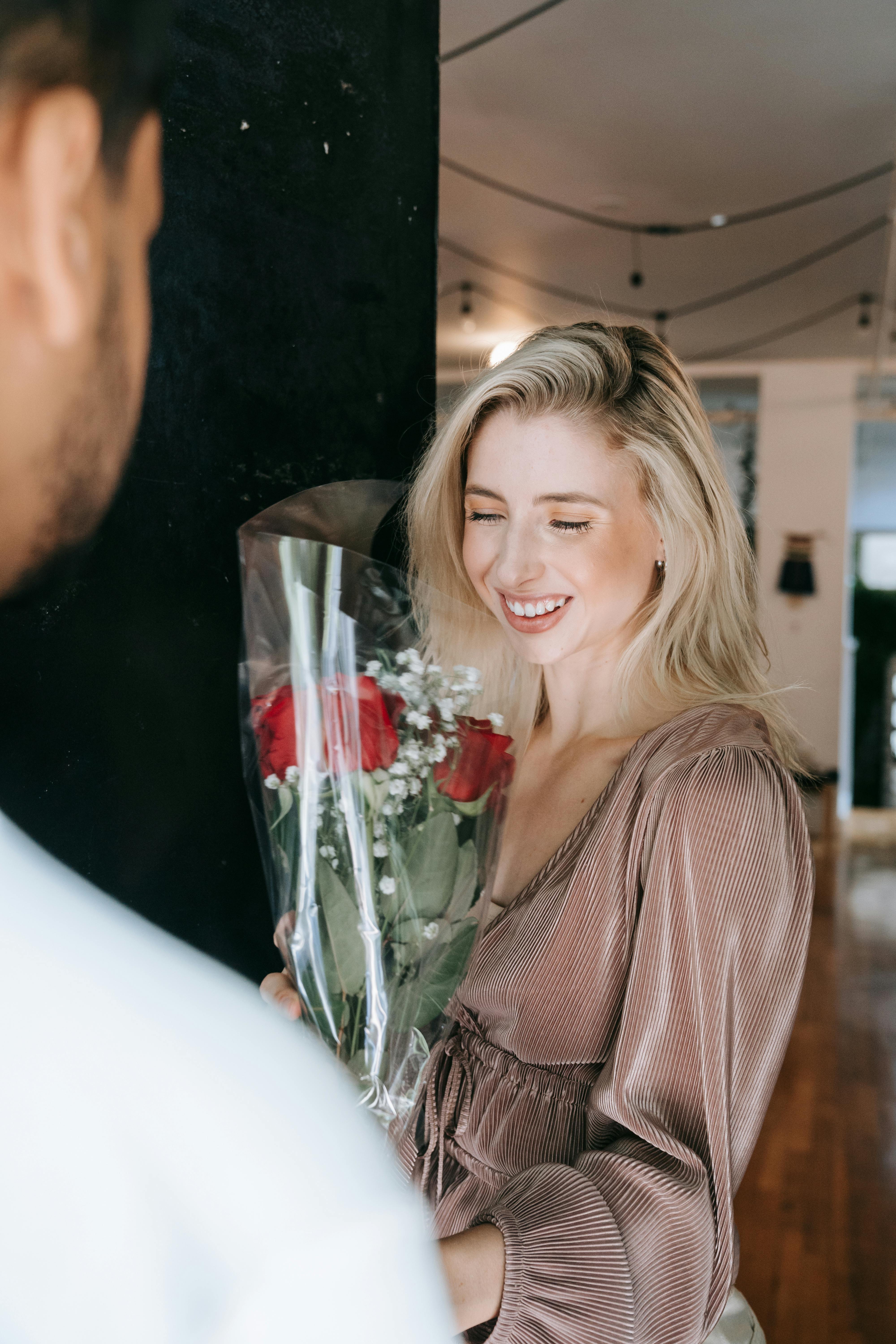 Woman Receiving Red Roses at an Entrance · Free Stock Photo