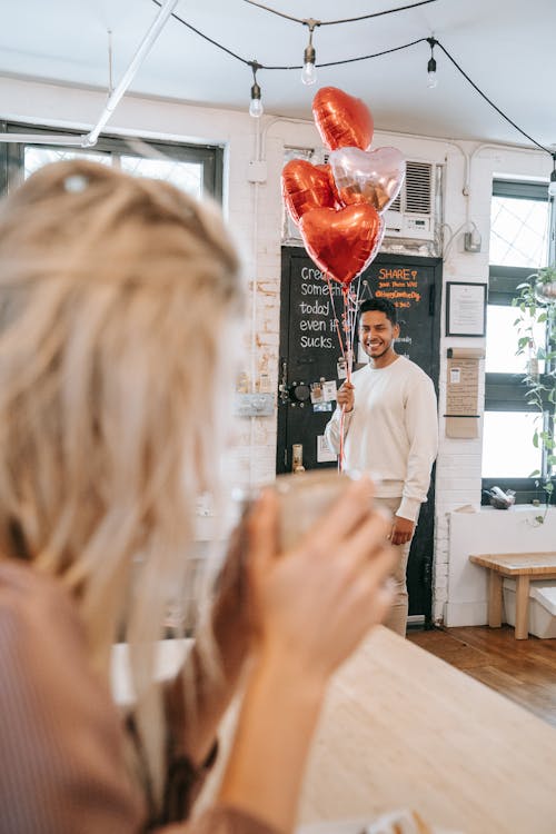 Man in White Sweater Holding Balloons