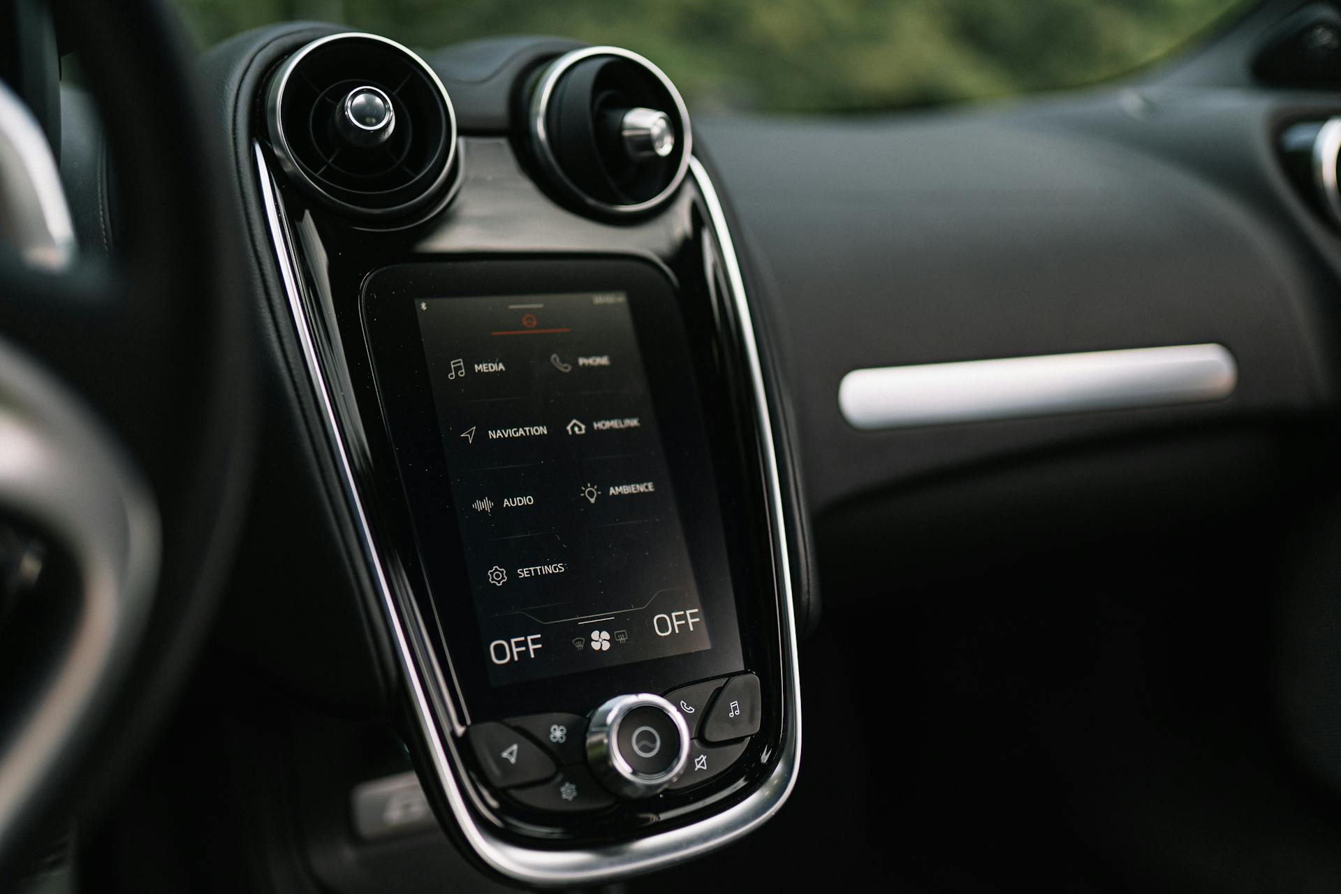 Close-up of a sleek car dashboard featuring a modern touchscreen interface for media and navigation controls.