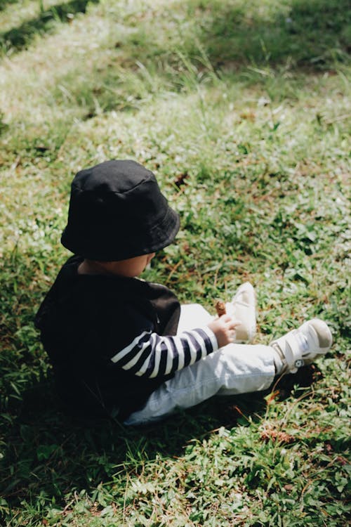 Free A Toddler Sitting on the Green Grass Stock Photo