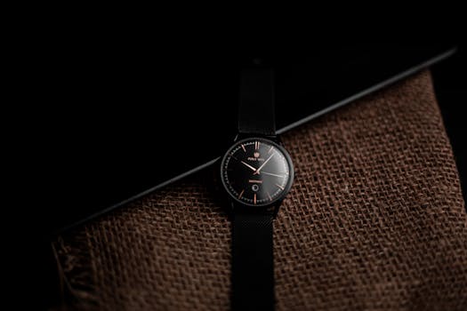 Stylish black wristwatch displayed on burlap with a dark elegant background.
