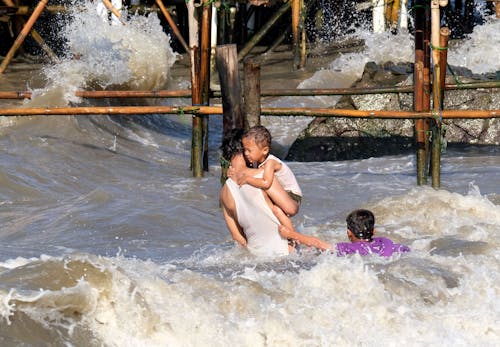 A Person in White Tank Top Carrying a Boy in White Tank Top