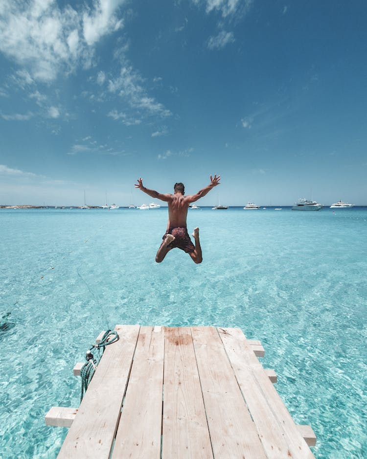 Man Jumping From The Dock Into The Sea