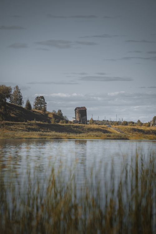 Free Serene landscape featuring an abandoned barn by a lake under a cloudy sky in Emva, Russia. Stock Photo