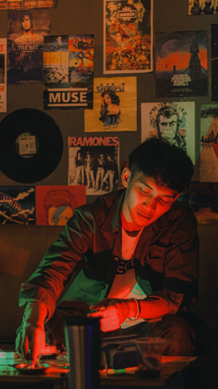 Photo Of A Man Sitting By A Wall With Posters 