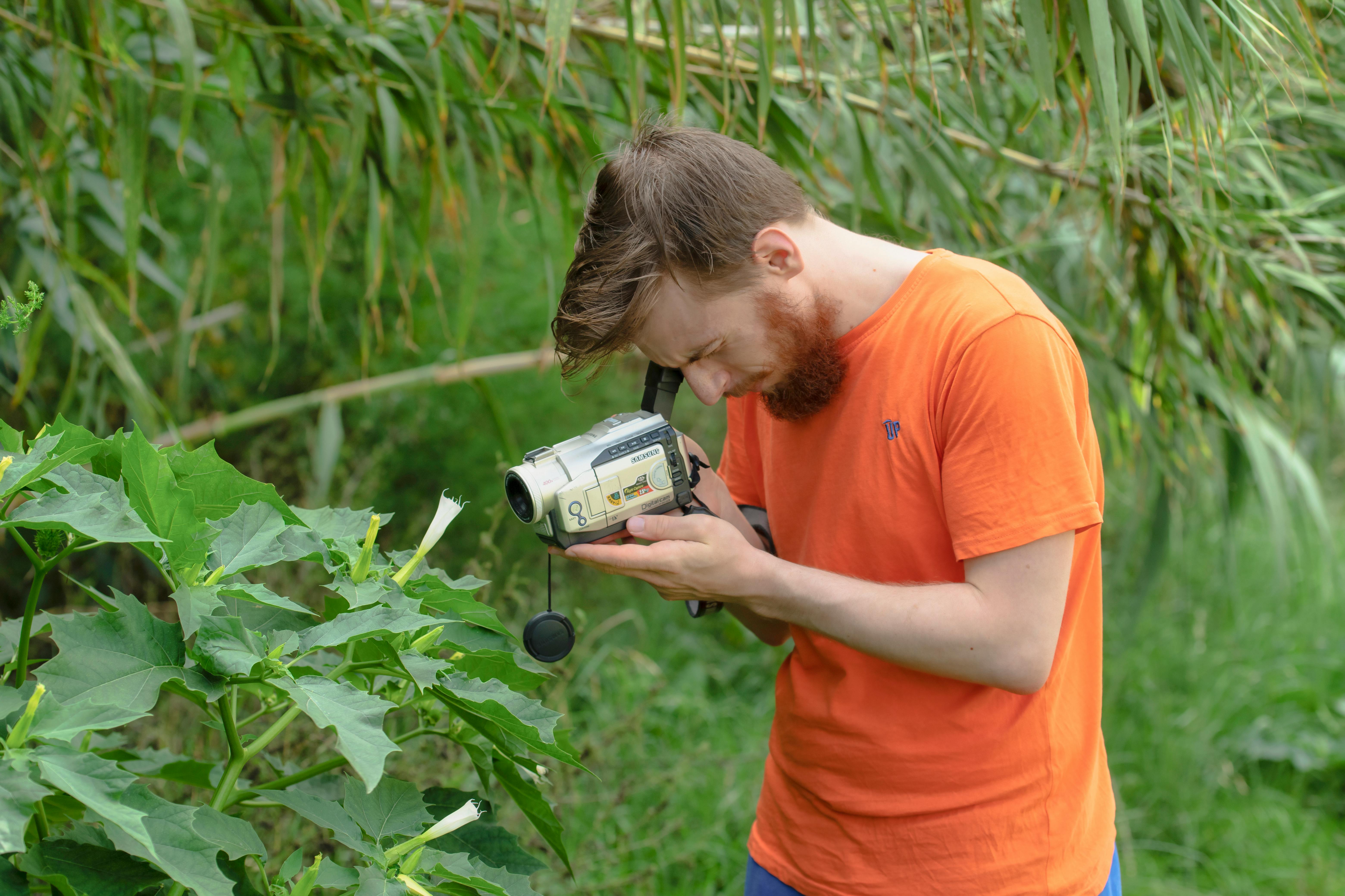 man in orange shirt holding a video camera