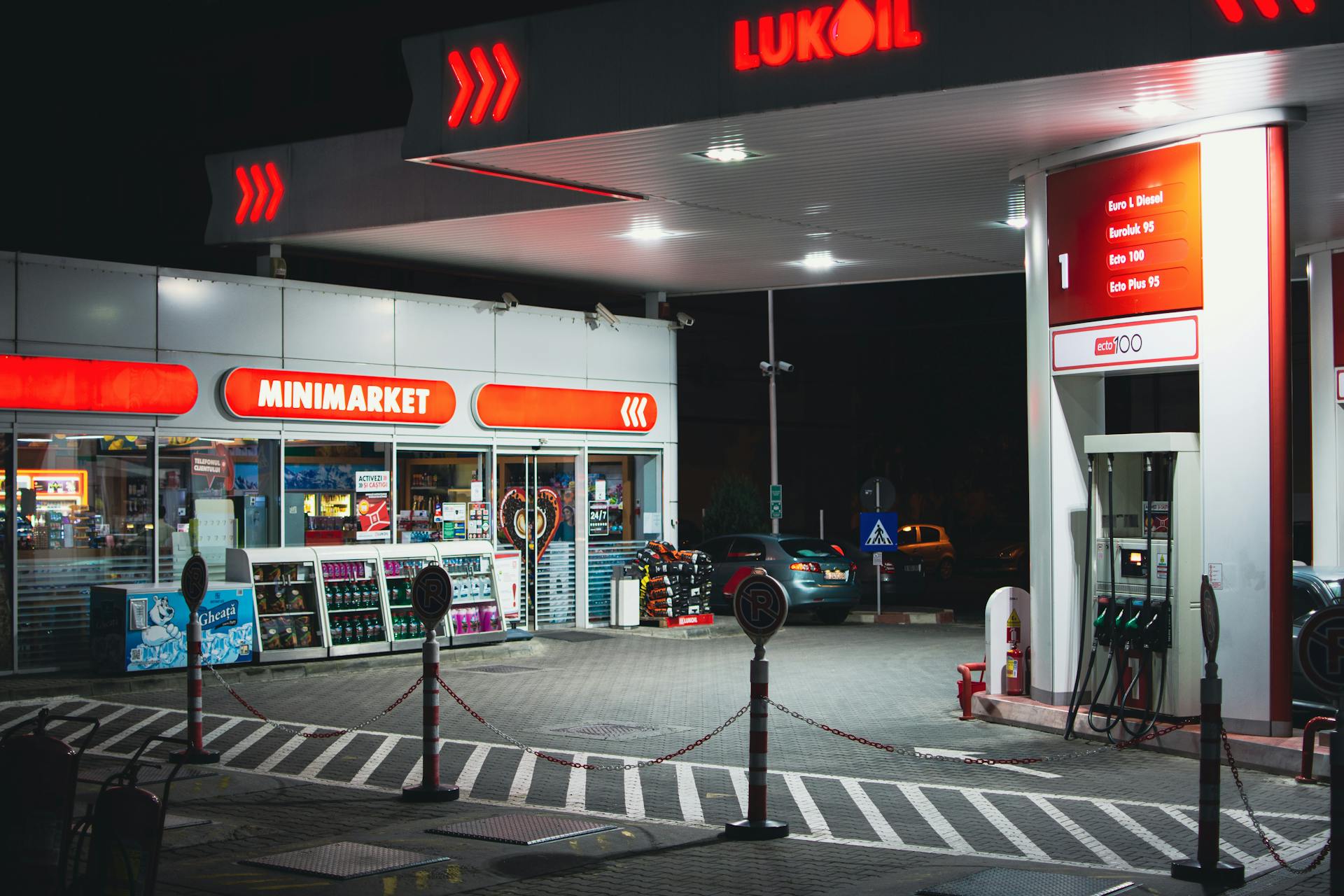 A brightly lit gas station with a minimarket in Bucharest during nighttime.