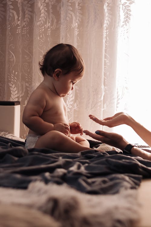 Topless Baby Sitting on Bed