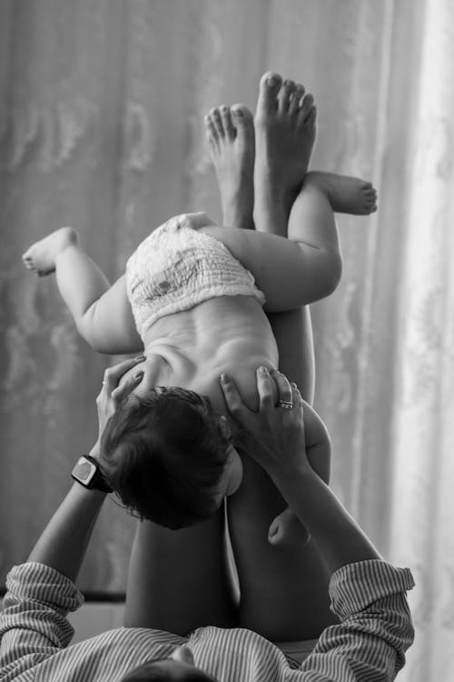 Grayscale Photo of a Person Playing with a Baby