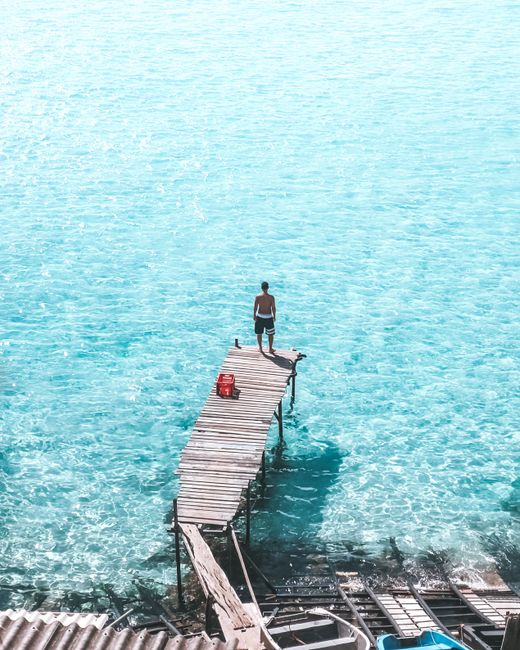 Enjoy the stunning azure waters and peaceful dock at Arraial do Cabo, Brazil, perfect for a summer escape.