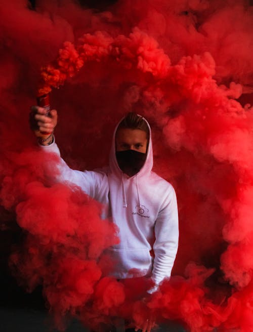 Man in White Hoodie Holding a Smoke Bomb