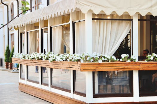 Elegant outdoor restaurant with white flowers and curtains, offering a cozy and inviting ambiance.