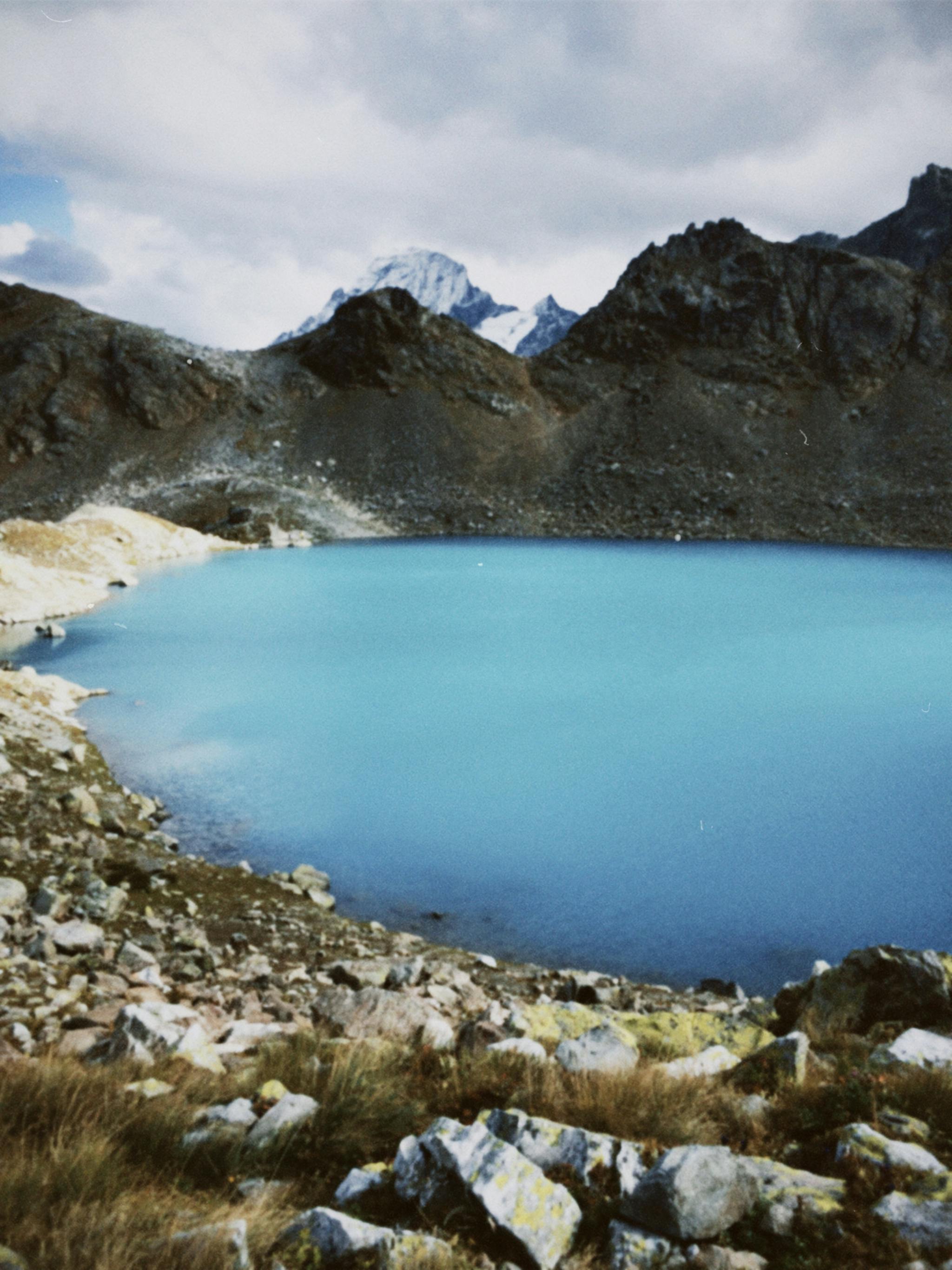 A serene mountain lake with clear blue water surrounded by rocky peaks.