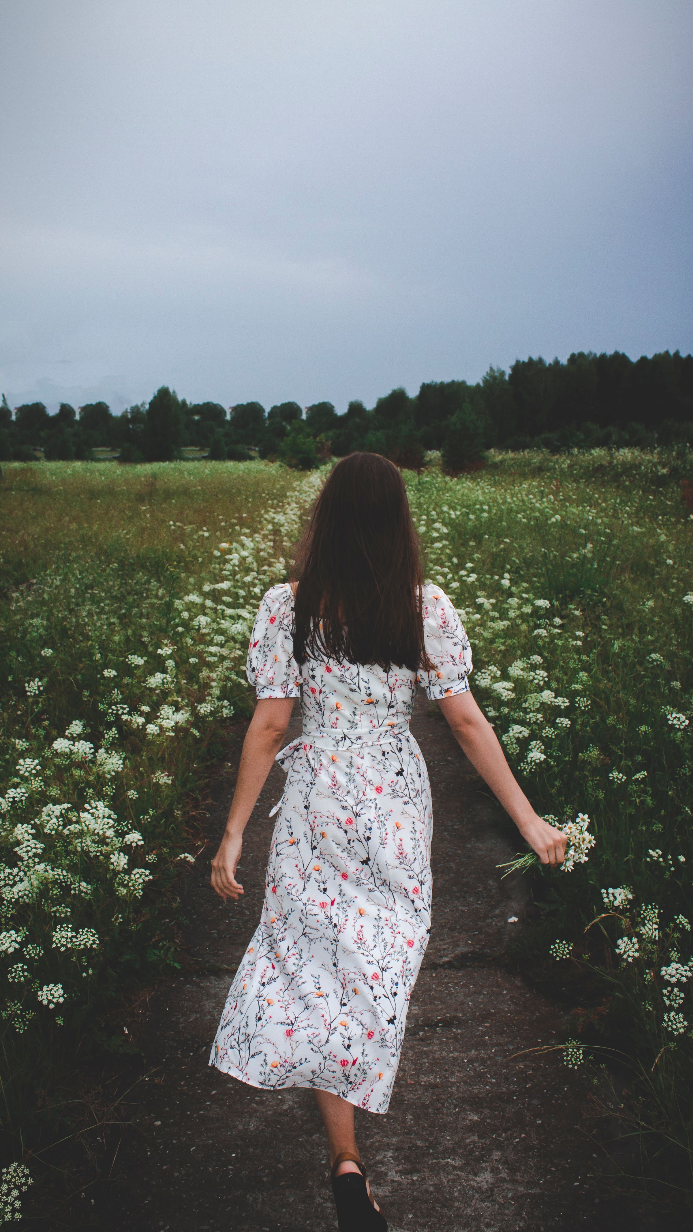 Woman in White Floral Dress Walking Beside Grass Field · Free Stock Photo