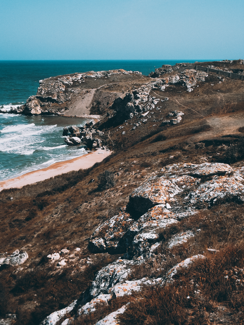 Free Explore the rugged cliffs and waves crashing on a rocky coastline under a clear blue sky. Stock Photo