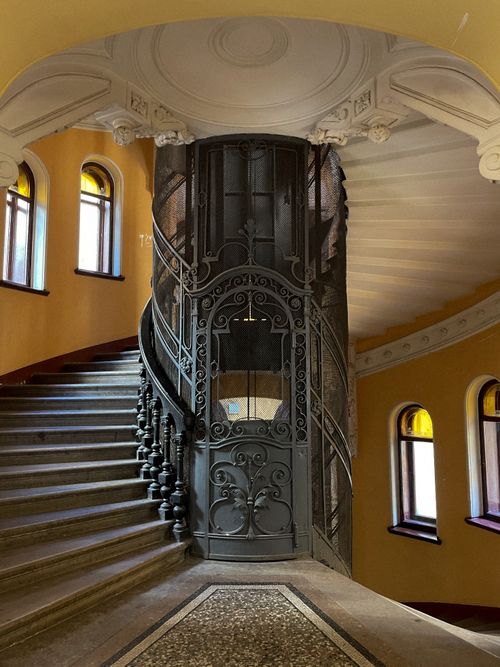 Free A vintage staircase with an ornate lift in a classic architectural setting, featuring elegant details and warm colors. Stock Photo