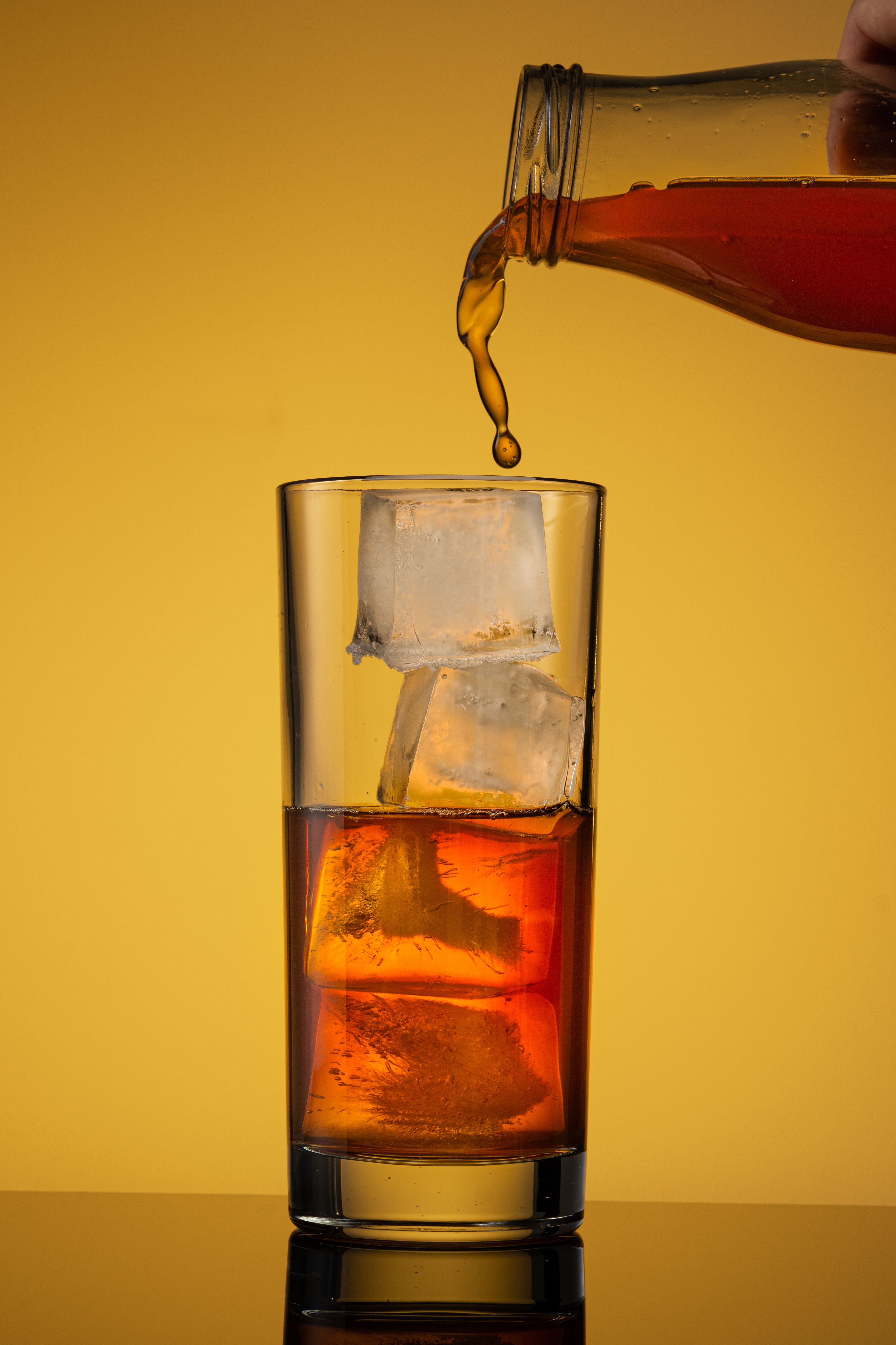Brown Liquid Pouring Into a Glass With Ice Cubes · Free Stock Photo