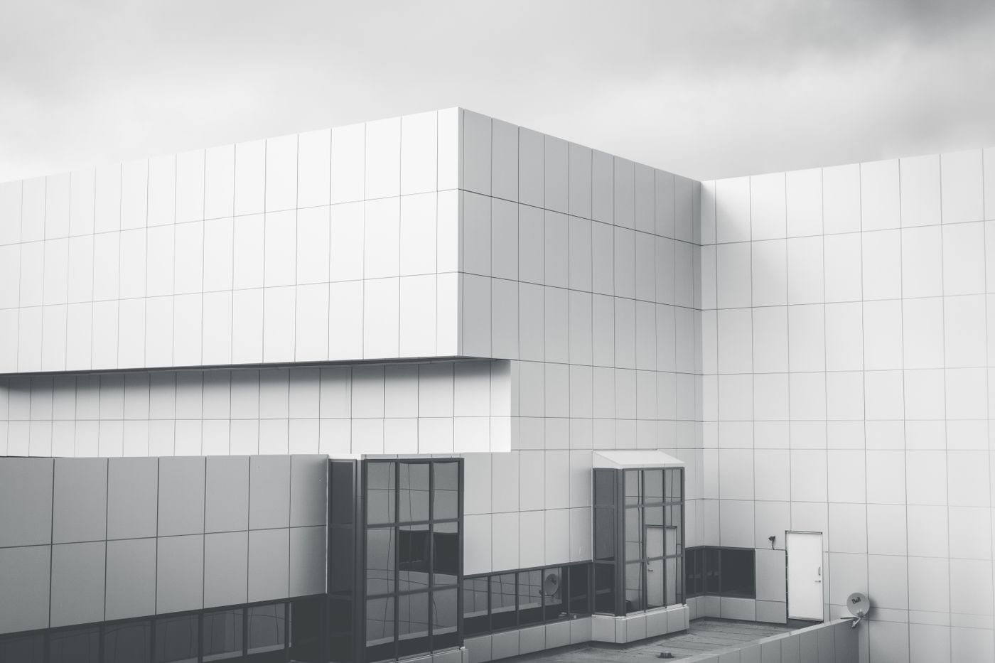 Minimalist white panel facade against a cloudy sky