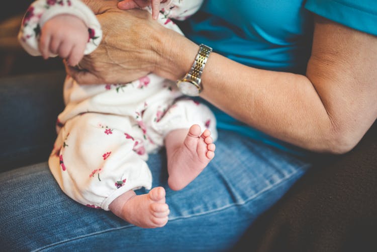 Person Holding Baby In White Onesie