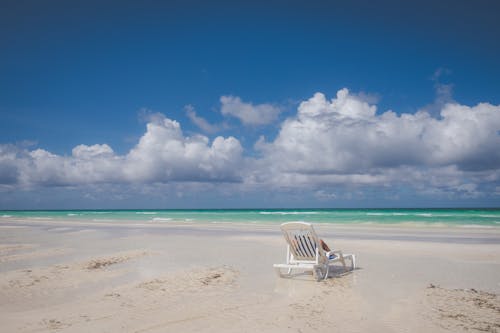 White Beach Chair on the Sea Shore under the Cloudy Blue Sky