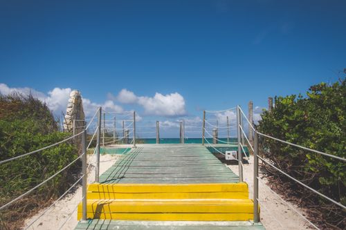 Free A vibrant boardwalk leading to a stunning beach with clear skies and ocean views. Stock Photo