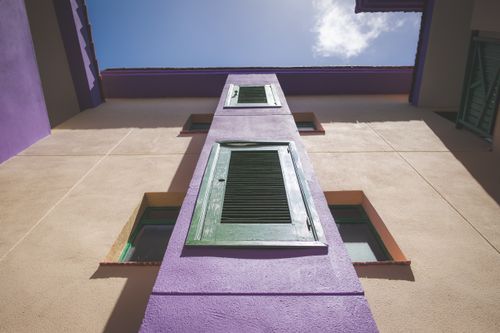 Free Low-angle view of a colorful facade featuring green shutters against a clear sky. Stock Photo