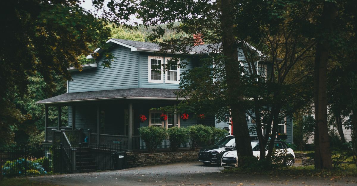 A cozy two-story suburban house nestled among lush trees, conveying serenity and seclusion.