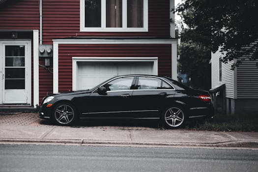 Elegant black car parked in front of a red residential house, showcasing urban lifestyle.