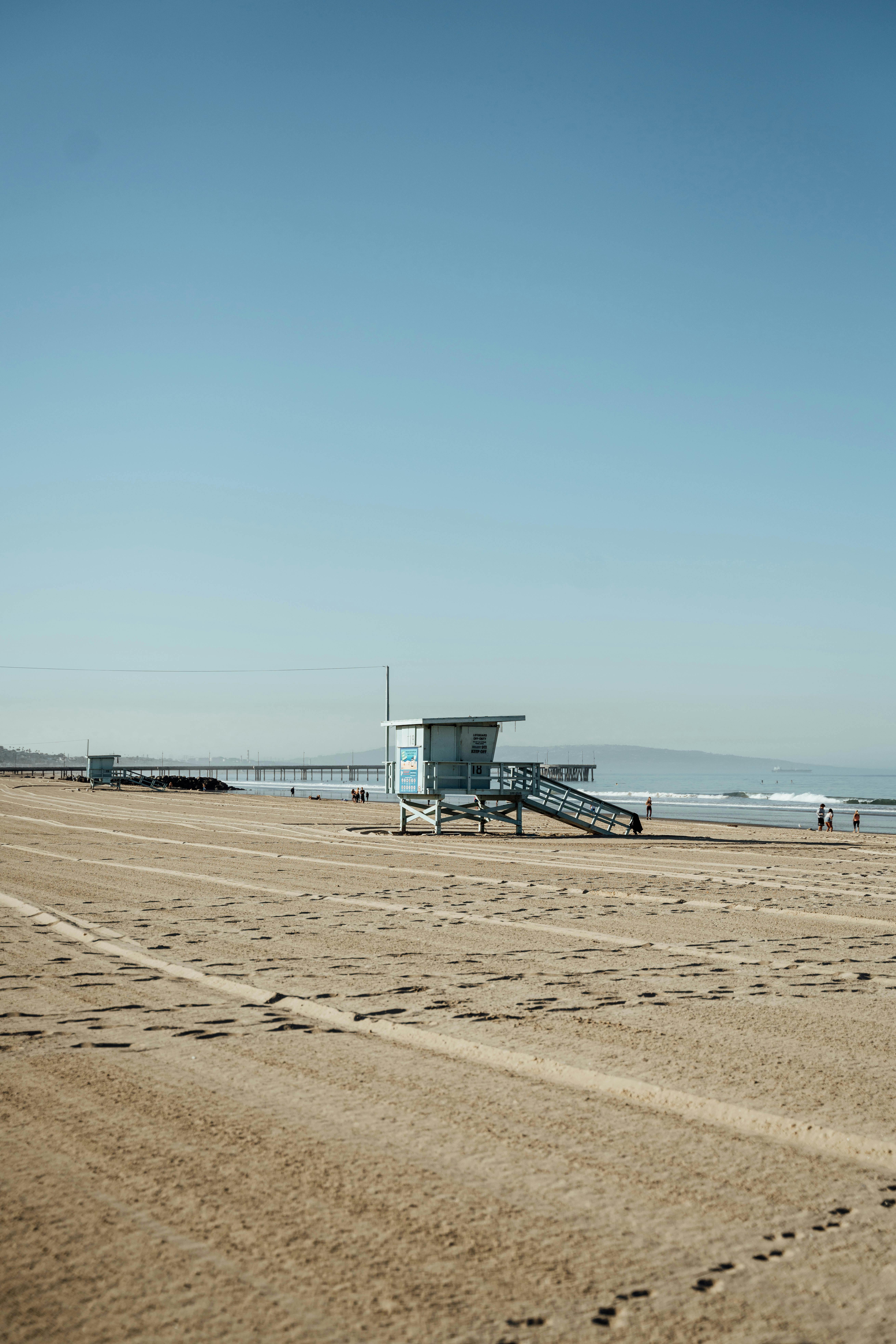 Peaceful beach scene featuring a solitary lifeguard station with a bright blue sky backdrop.