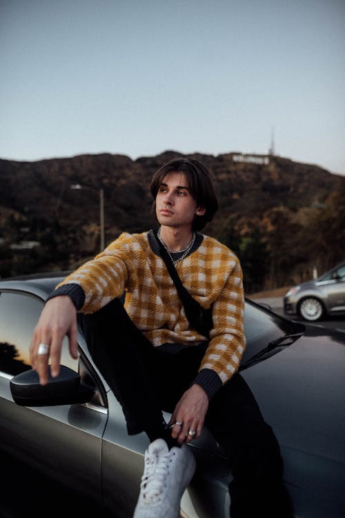 Man in a Checkered Long Sleeves Leaning on a Car