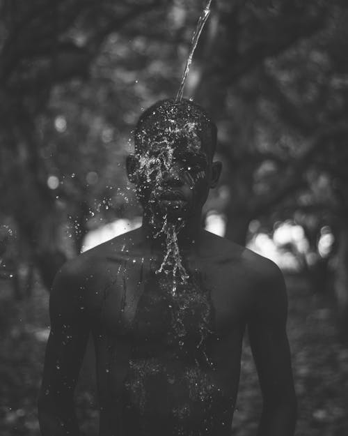 Grayscale Photo of Water Being Poured on a Man