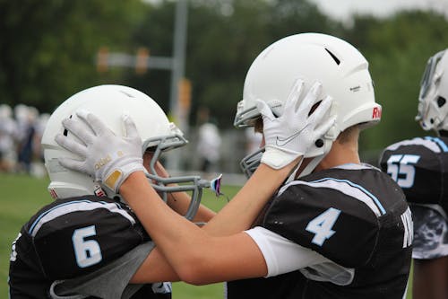 Photograph of Football Players Holding Each Other's Helmets