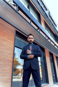 Low-angle shot of a businessman in a suit outside a modern office building.