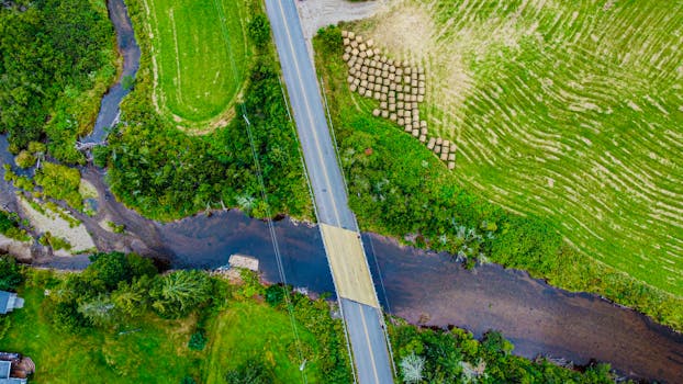 Drone shot of a bridge over a river in rural Nova Scotia, surrounded by fields.