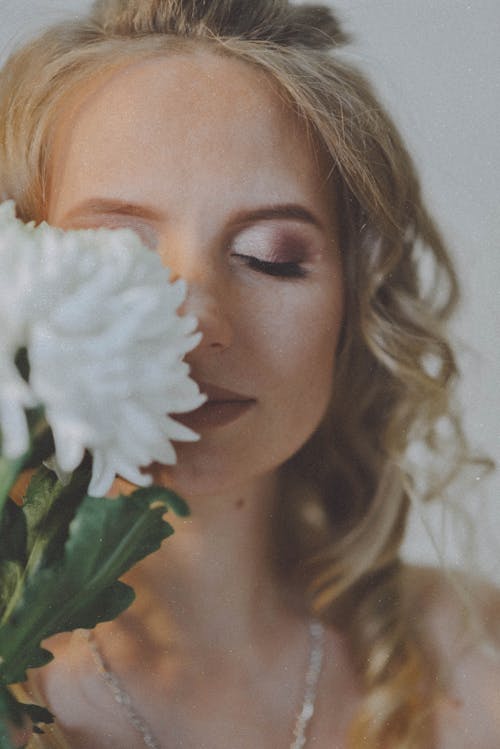 Close-Up Shot of a Beautiful Woman Smelling White Flowers