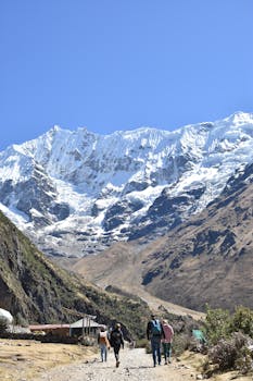 Explorers trekking along a trail in the stunning Andes Mountains with snow-capped peaks.