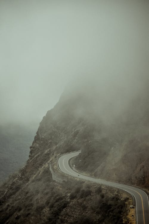 Free Gray Asphalt Road in a Mountainside covered in Fog Stock Photo
