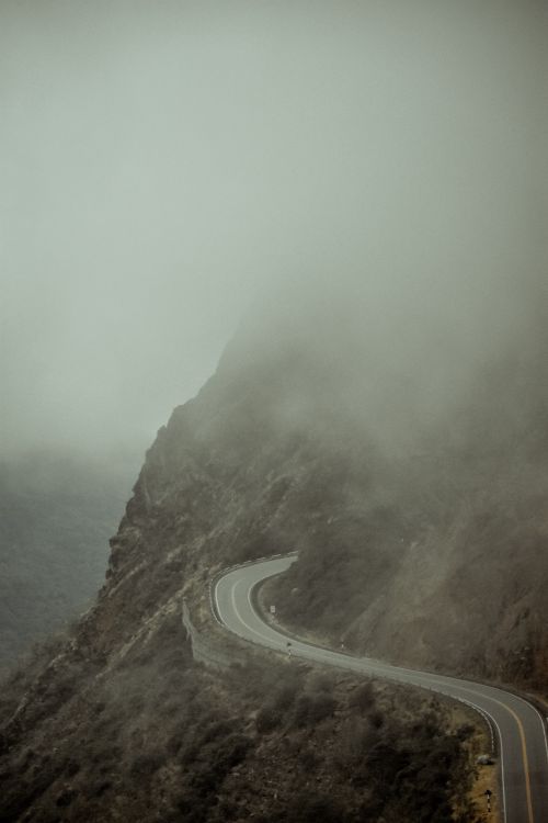 Free A foggy, winding road through the misty mountains of Peru, showcasing the country's dramatic landscapes. Stock Photo