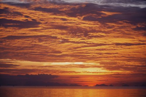 Free A stunning orange sunset over the ocean with dramatic clouds, capturing nature's beauty at dusk. Stock Photo