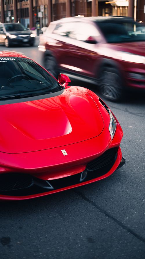 Free A striking red Ferrari supercar parked on a bustling Toronto street, capturing urban elegance. Stock Photo