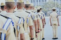 Group of Men in White Uniform Standing on White Sand