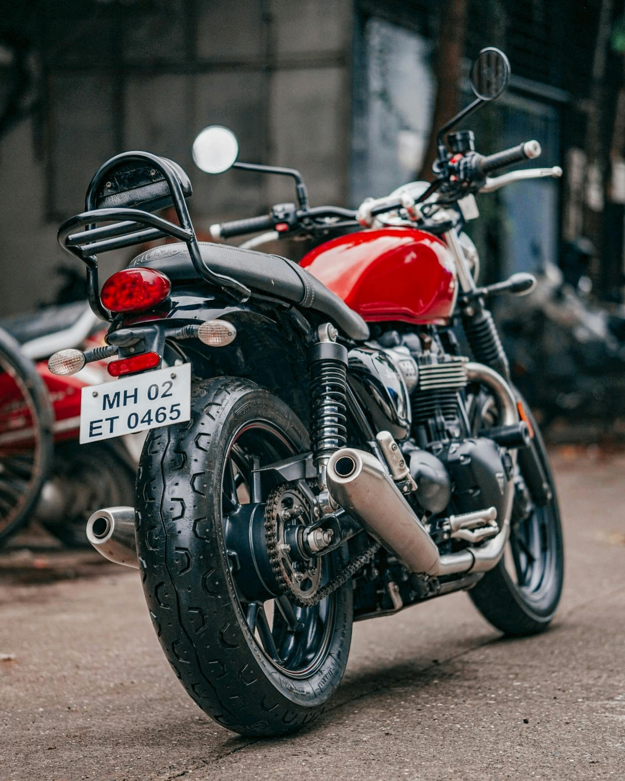 Free Rear view of a classic red motorcycle with license plate in a city setting. Stock Photo