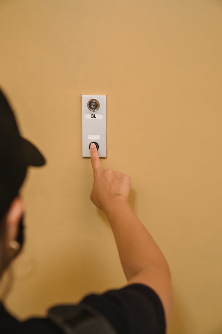 A Person Pressing A Doorbell